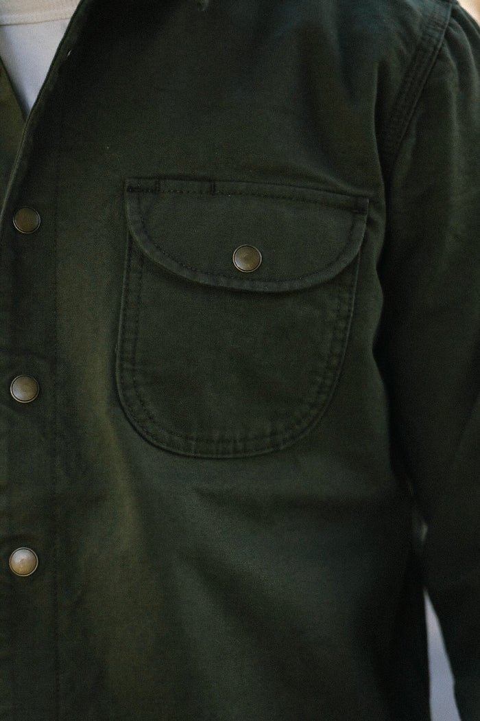 Close-up of dark green button-up work jacket with flap chest pocket and metal snap buttons