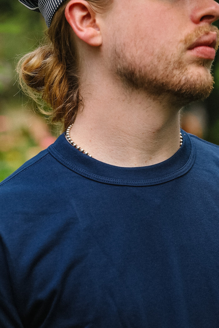 Man wearing a blue shirt with a blurred natural background